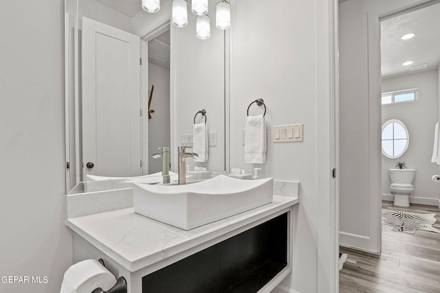 bathroom featuring wood-type flooring, vanity, and toilet