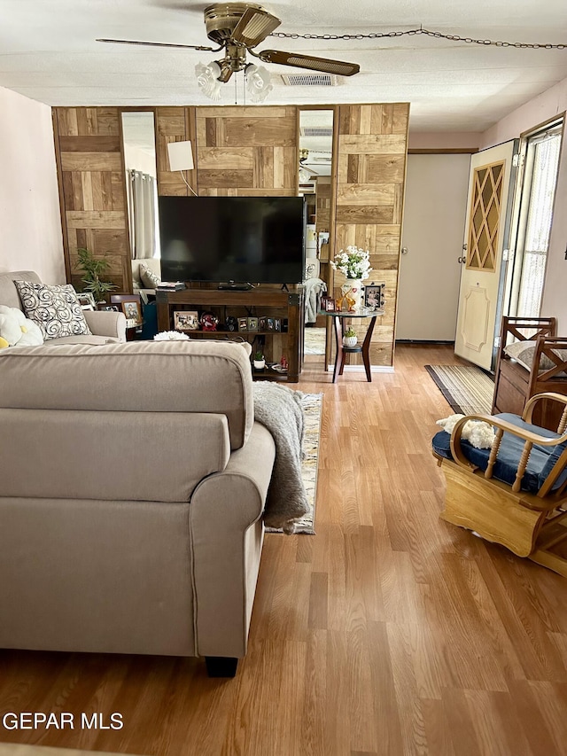 living room featuring wooden walls, ceiling fan, and hardwood / wood-style flooring