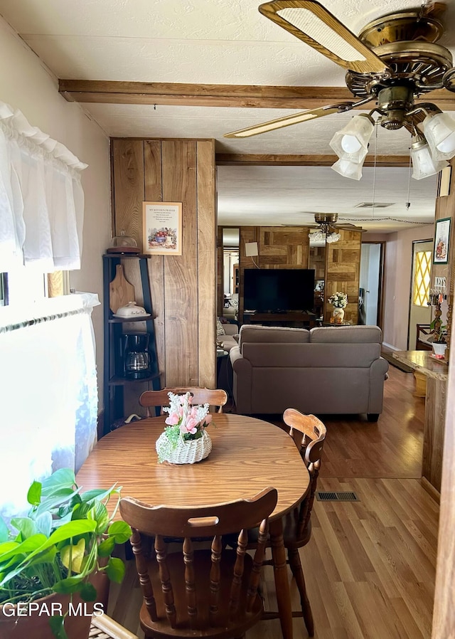 dining room with hardwood / wood-style flooring, ceiling fan, and beam ceiling