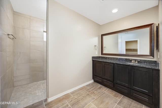 bathroom featuring tiled shower and vanity