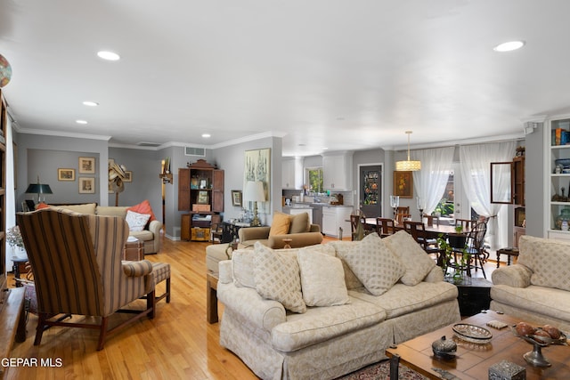 living room with crown molding, recessed lighting, visible vents, and light wood-style floors