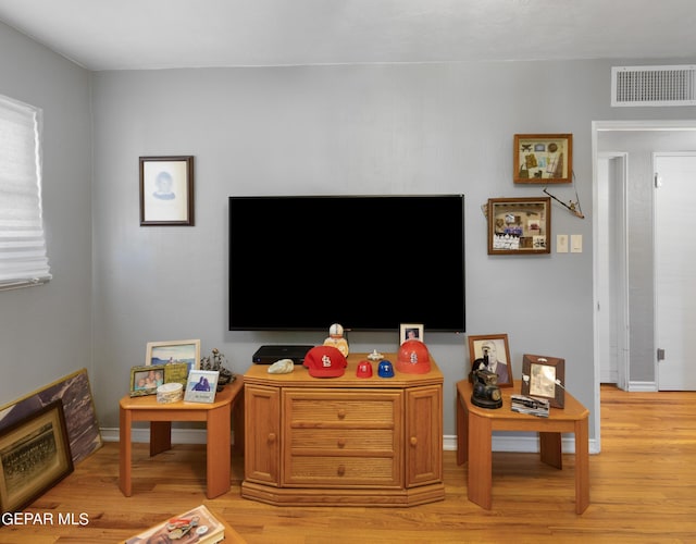 living area featuring light wood-style flooring, visible vents, and baseboards