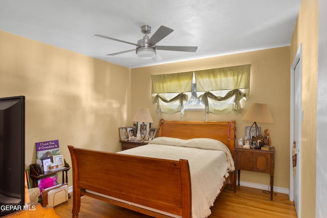 bedroom featuring ceiling fan, baseboards, and wood finished floors