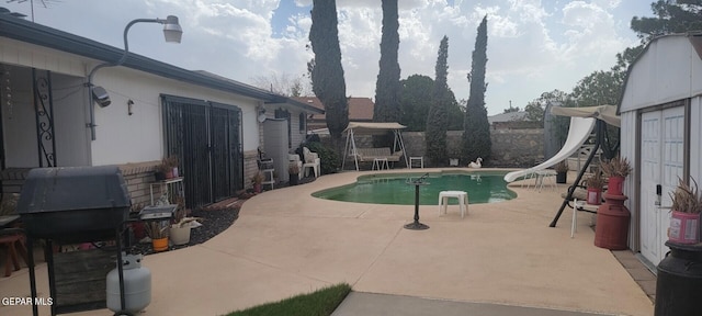 view of pool with a water slide and a patio