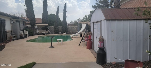 view of pool featuring an outdoor structure, a patio, and a water slide