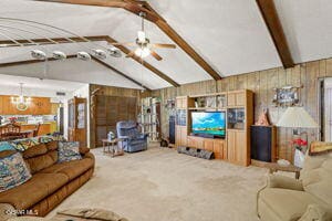 living room featuring wooden walls, lofted ceiling with beams, ceiling fan, and carpet flooring