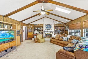 living room with ceiling fan, lofted ceiling with beams, and wood walls