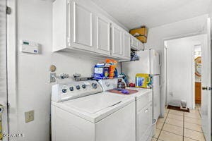 clothes washing area with light tile patterned floors and washer and dryer