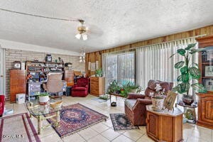 living room featuring light tile patterned floors, brick wall, a textured ceiling, and ceiling fan