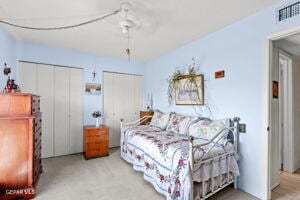 bedroom with ceiling fan, multiple closets, and carpet flooring