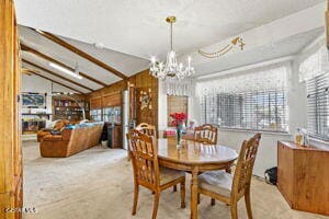 dining space with vaulted ceiling with beams and a chandelier