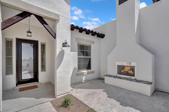 doorway to property with exterior fireplace and a patio area