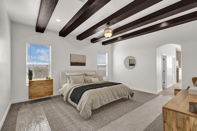 bedroom featuring beamed ceiling, ceiling fan, multiple windows, and carpet