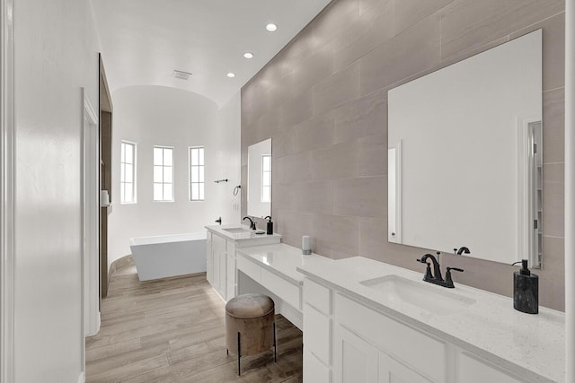 bathroom with hardwood / wood-style floors, brick ceiling, lofted ceiling, vanity, and a bath