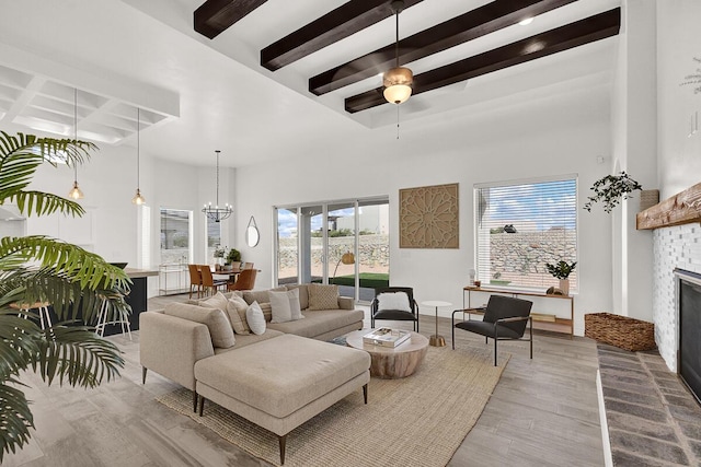 living room with ceiling fan with notable chandelier, a brick fireplace, and a high ceiling