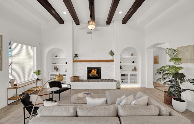 living room featuring beam ceiling, light wood-type flooring, and built in shelves