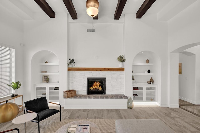 living room with built in shelves, a high ceiling, and hardwood / wood-style flooring