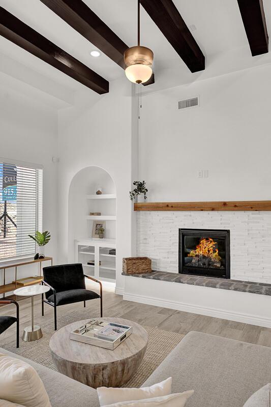 living room featuring built in shelves, light hardwood / wood-style flooring, and beamed ceiling