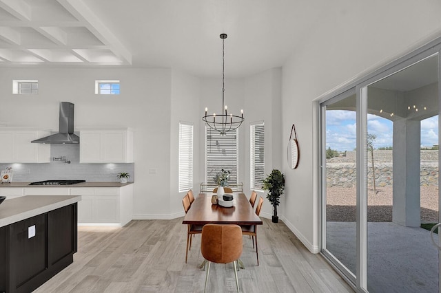 dining area with an inviting chandelier, coffered ceiling, light hardwood / wood-style floors, and beamed ceiling