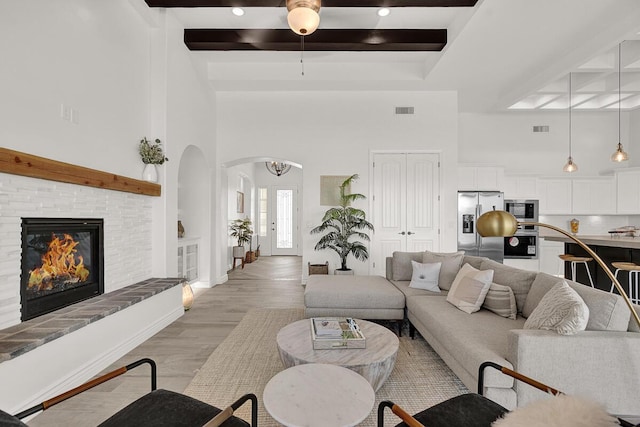 living room with beam ceiling, light hardwood / wood-style floors, and a high ceiling