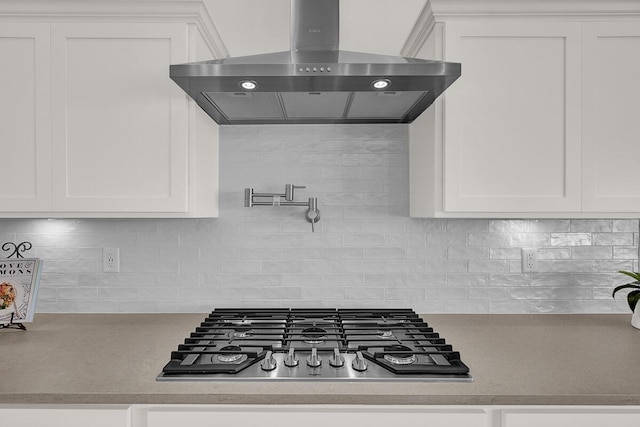 kitchen featuring white cabinets, stainless steel gas cooktop, backsplash, and wall chimney exhaust hood