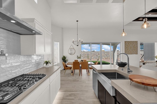 kitchen featuring white cabinetry, tasteful backsplash, hanging light fixtures, stainless steel appliances, and wall chimney range hood