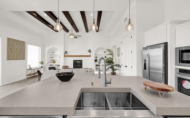 kitchen featuring stainless steel appliances, beam ceiling, hanging light fixtures, and built in features