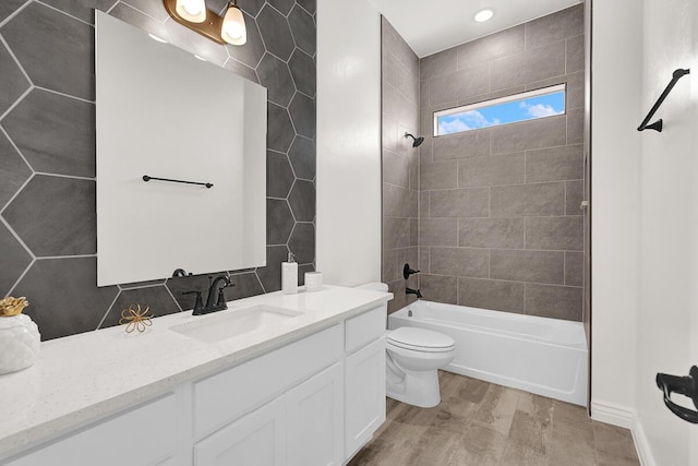 full bathroom featuring tiled shower / bath combo, vanity, wood-type flooring, and toilet