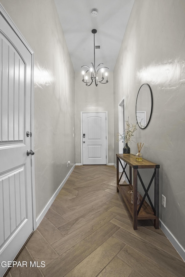 doorway with dark parquet flooring and a chandelier