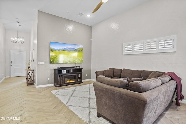 living room featuring a high ceiling, light parquet flooring, and ceiling fan with notable chandelier