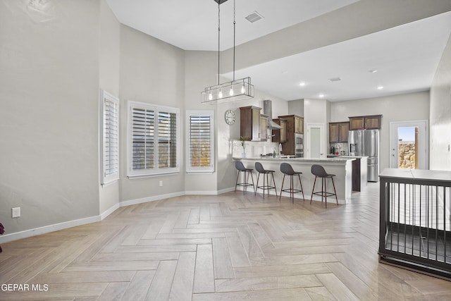 kitchen featuring light parquet flooring, a kitchen breakfast bar, hanging light fixtures, stainless steel fridge, and kitchen peninsula