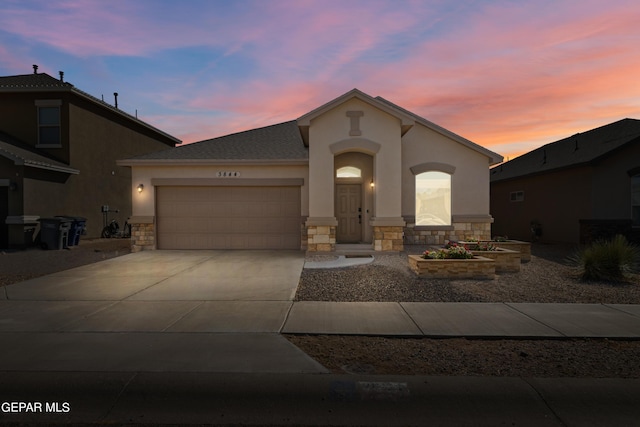 view of front of house featuring driveway, stone siding, an attached garage, and stucco siding