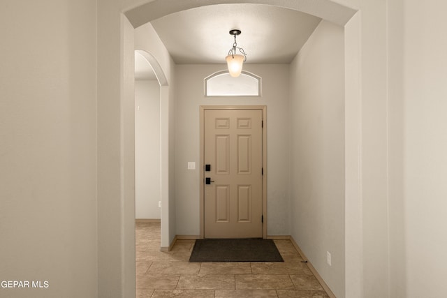 doorway to outside with arched walkways and baseboards