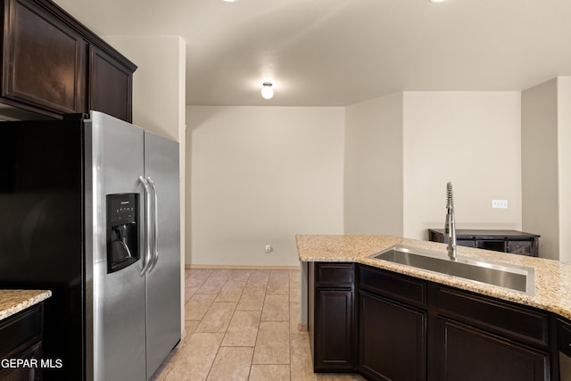 kitchen featuring wood finish floors, stainless steel refrigerator with ice dispenser, a sink, dark brown cabinets, and light stone countertops