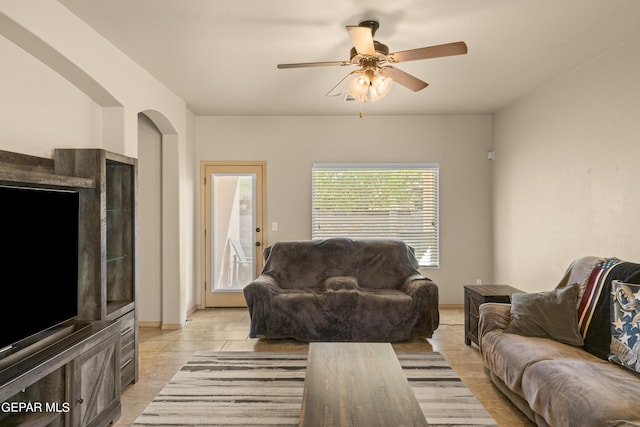 living area with ceiling fan, light tile patterned floors, and arched walkways