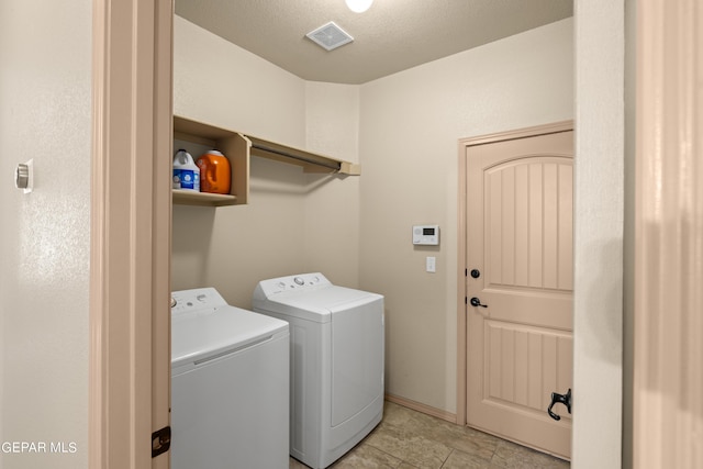 clothes washing area featuring washer and clothes dryer, visible vents, a textured ceiling, laundry area, and baseboards