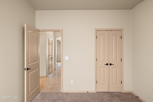 unfurnished bedroom featuring a closet and light tile floors