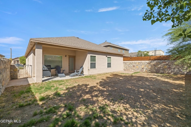 back of property with roof with shingles, a fenced backyard, a patio, and stucco siding