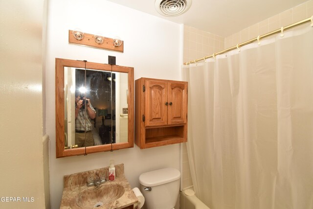 full bathroom with sink, shower / bath combo with shower curtain, and toilet