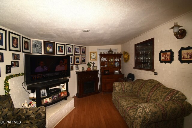 living room with a textured ceiling, brick wall, and wood-type flooring