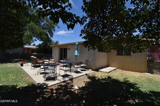 rear view of property featuring a yard and a patio area