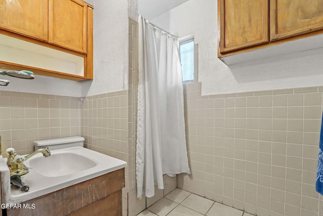 bathroom featuring walk in shower, vanity, tile patterned floors, and tile walls