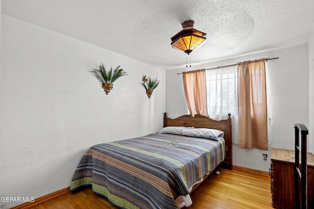 bedroom with a textured ceiling and light wood-type flooring