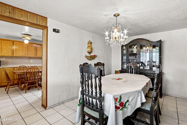 tiled dining room with a textured ceiling and an inviting chandelier