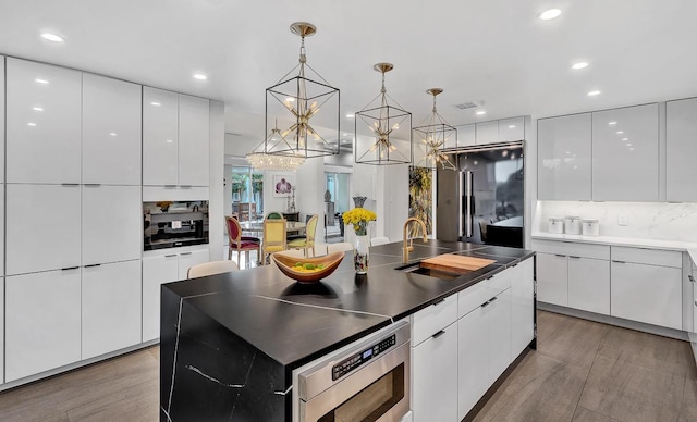 928 Singing Hills Dr, El Paso, TX 79912 - kitchen with stainless steel microwave, recessed lighting, a chandelier, white cabinetry, and modern cabinets