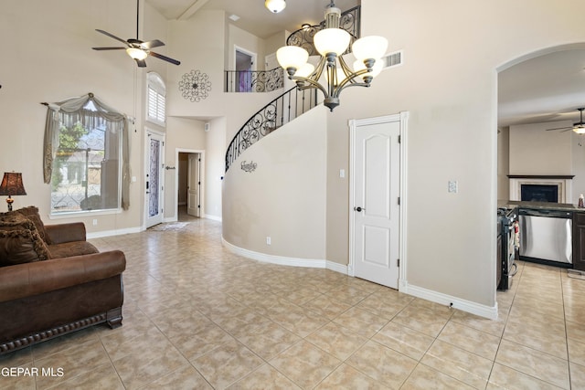 living room with ceiling fan with notable chandelier, a high ceiling, and light tile patterned flooring