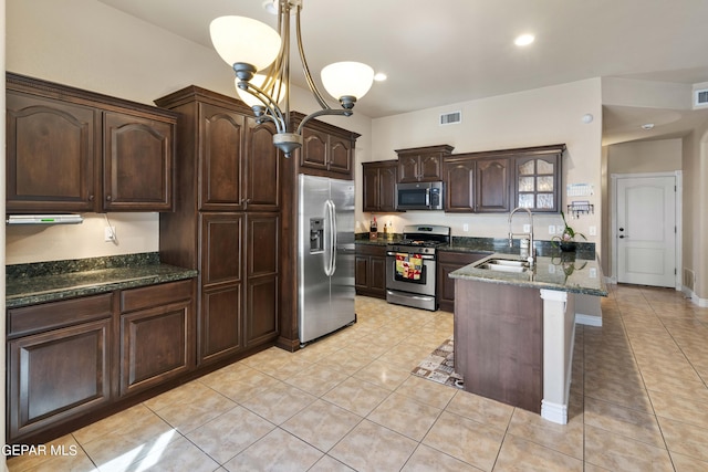 kitchen featuring appliances with stainless steel finishes, sink, light tile patterned flooring, a kitchen island with sink, and dark brown cabinetry