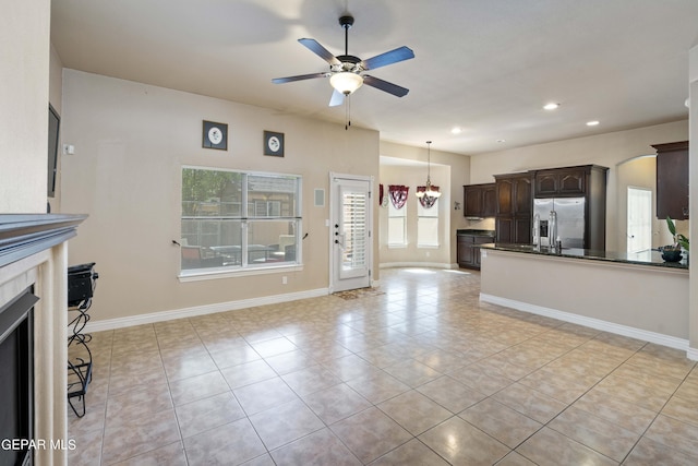 unfurnished living room featuring a fireplace, ceiling fan with notable chandelier, and light tile patterned floors