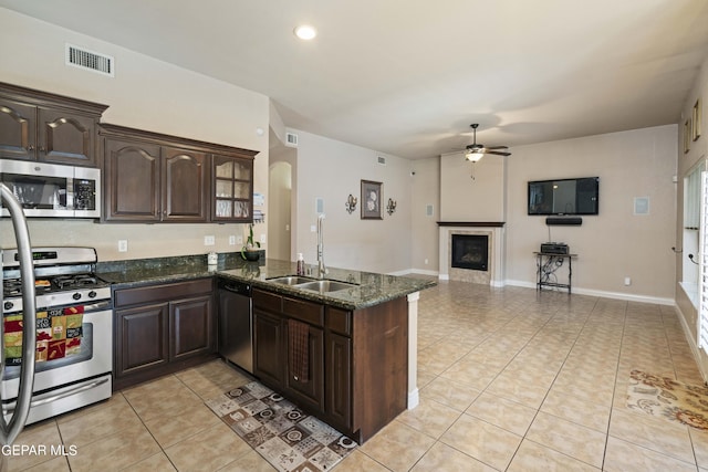 kitchen featuring sink, kitchen peninsula, stainless steel appliances, and dark stone counters