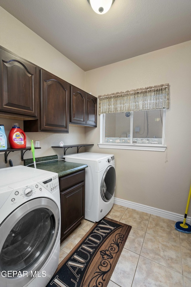 laundry room featuring washing machine and dryer, light tile patterned floors, and cabinets